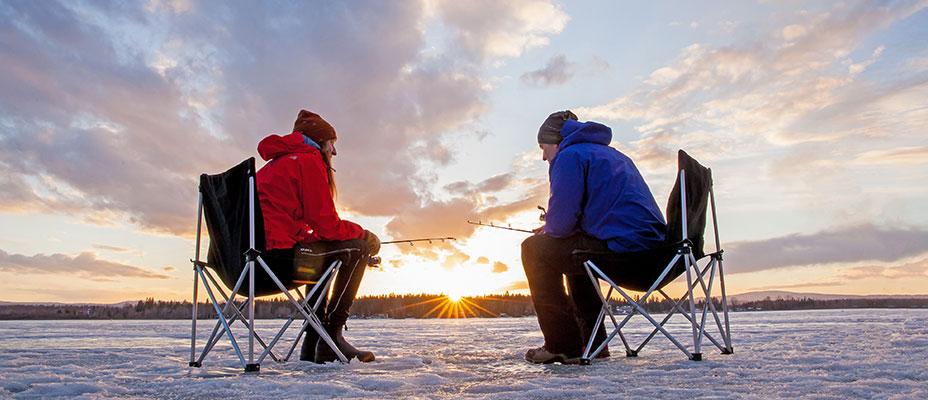 Two people ice fishing during a beautiful sunset